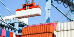 Crane loading a shipping container onto a cargo stack at an international port
